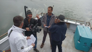 Director Brad Douglas and Cinematographer Chuck Greenwood discuss the look of a scene being filmed on the ocean off the coast of Brookings, Oregon. Also pictured are actors Jonny Lee and Mark Schneider.